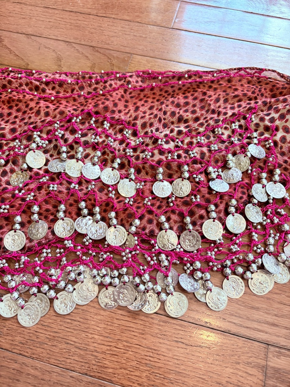 Pink belly dance hip scarf with silver coins and over a pink leopard print.
